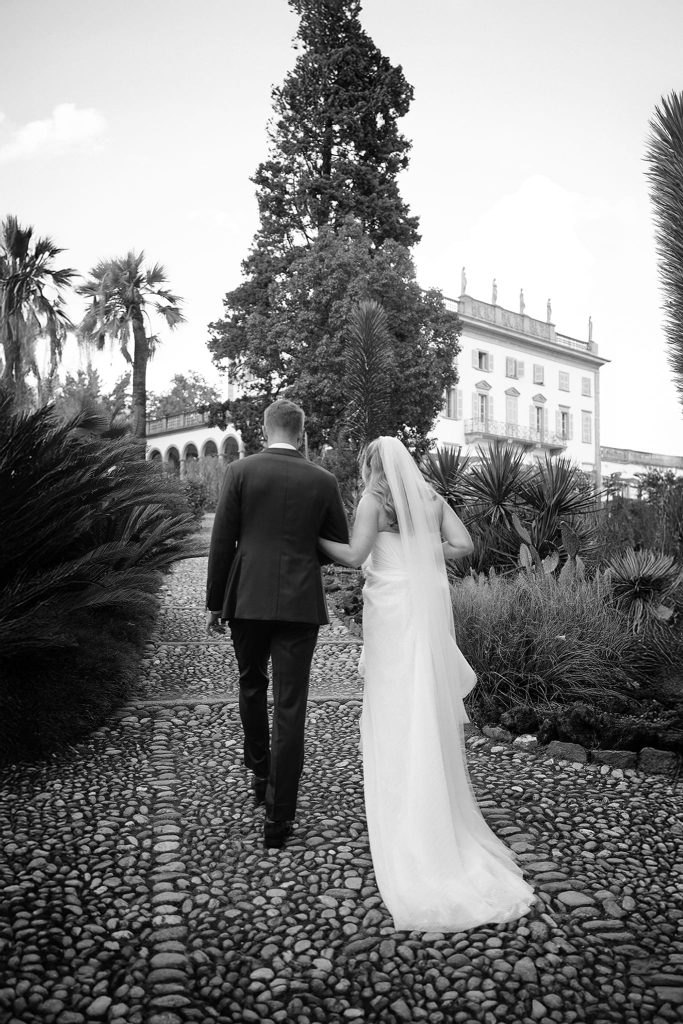 Newlyweds walking in the garden in front of an elegant villa